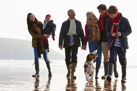 Active three generation family walking on the beach.